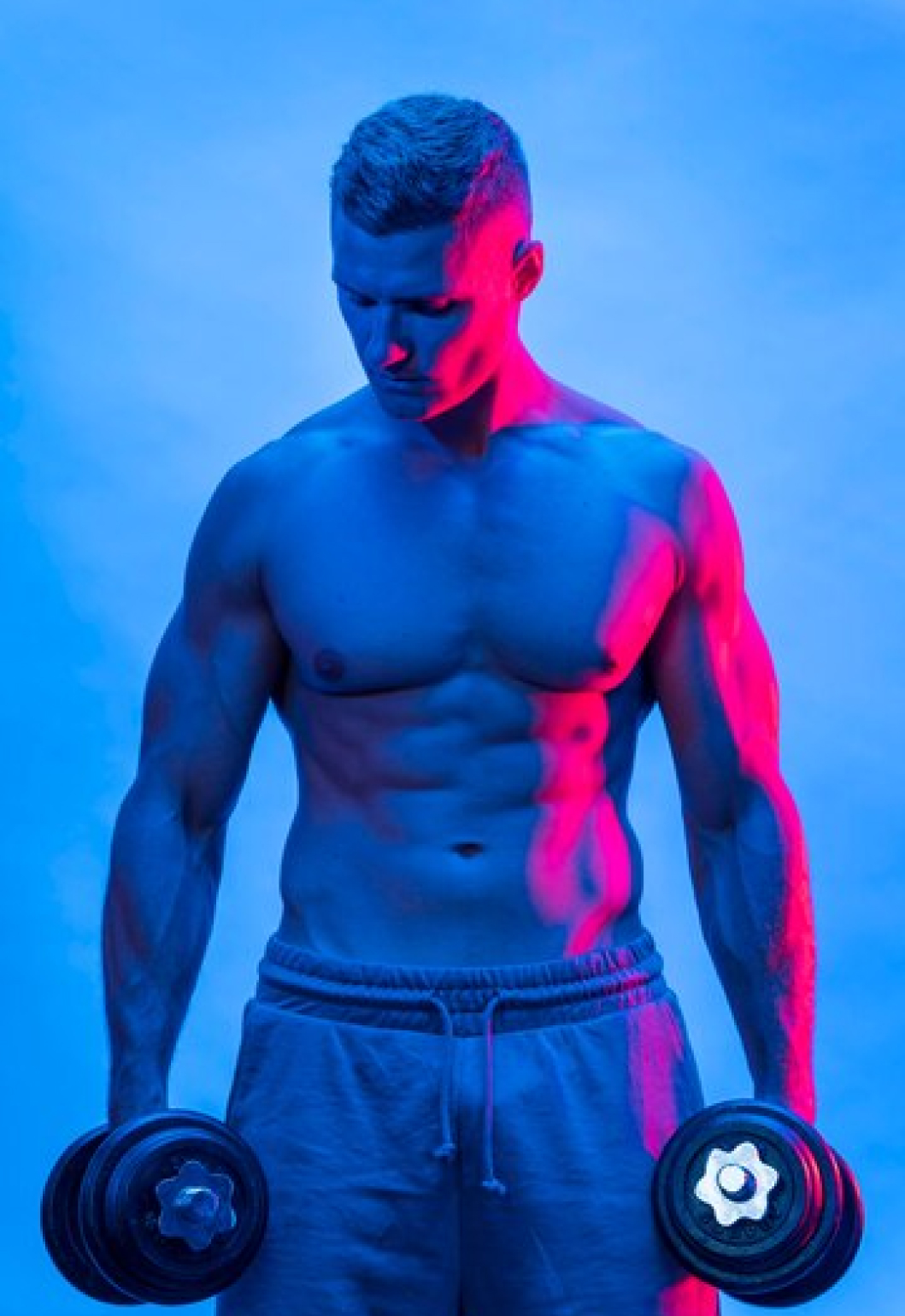 Спортивный мужчика держит в руках гантели